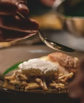 A chef finishing a dish by hand in the kitchen